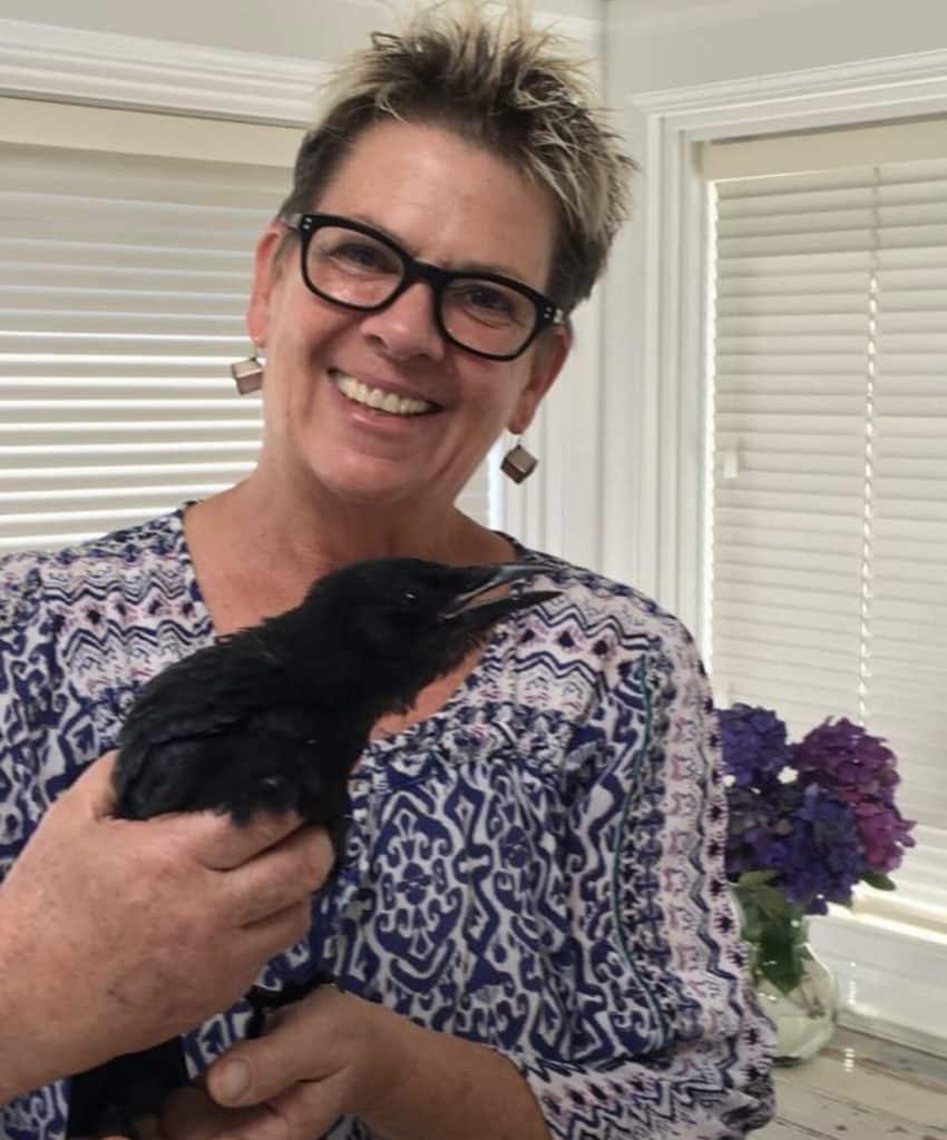 Chere Hickock smiling and holding a large black bird.