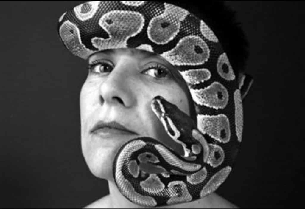 Black-and-white portrait of young Chere Hickock with a ball python draped around her face.